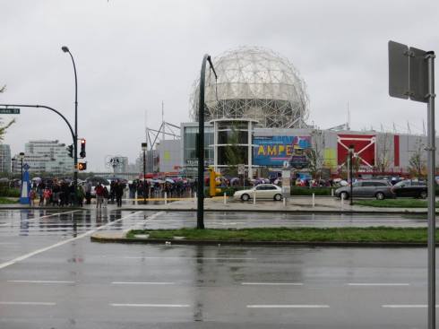 People lining up around the block in the rain, waiting to enter the Science World.
